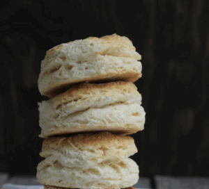 A stack of three flaky, round biscuits against a dark background.
