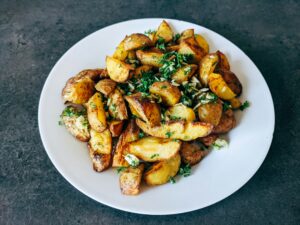Plate of roasted potato wedges with parsley and garlic.